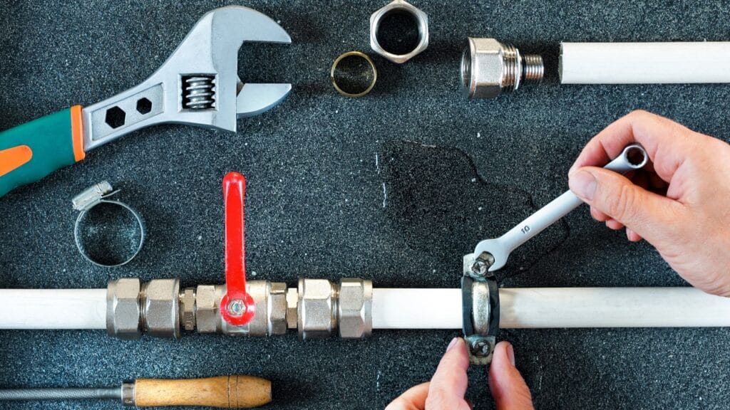 Plumber repairing a pipe valve with an adjustable wrench in West Linn