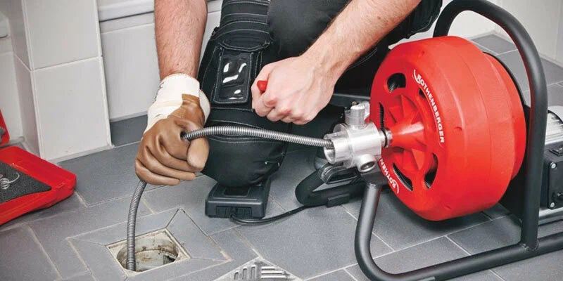 Plumber using a drain-cleaning machine in West Linn