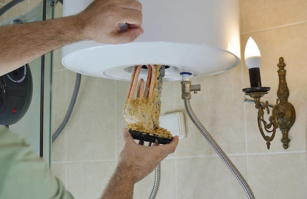 Technician removing mineral buildup from a water heater in West Linn