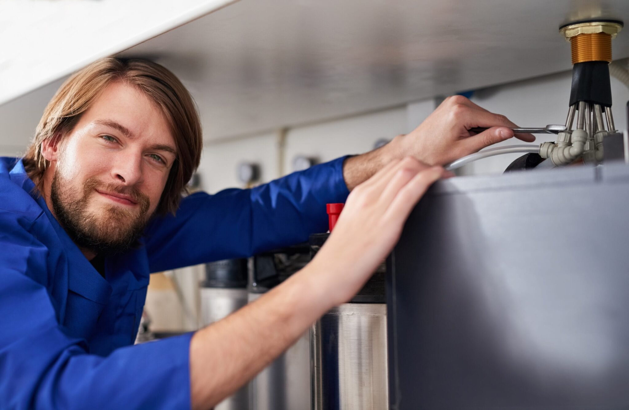 Technician servicing a residential water heater tank in West Linn