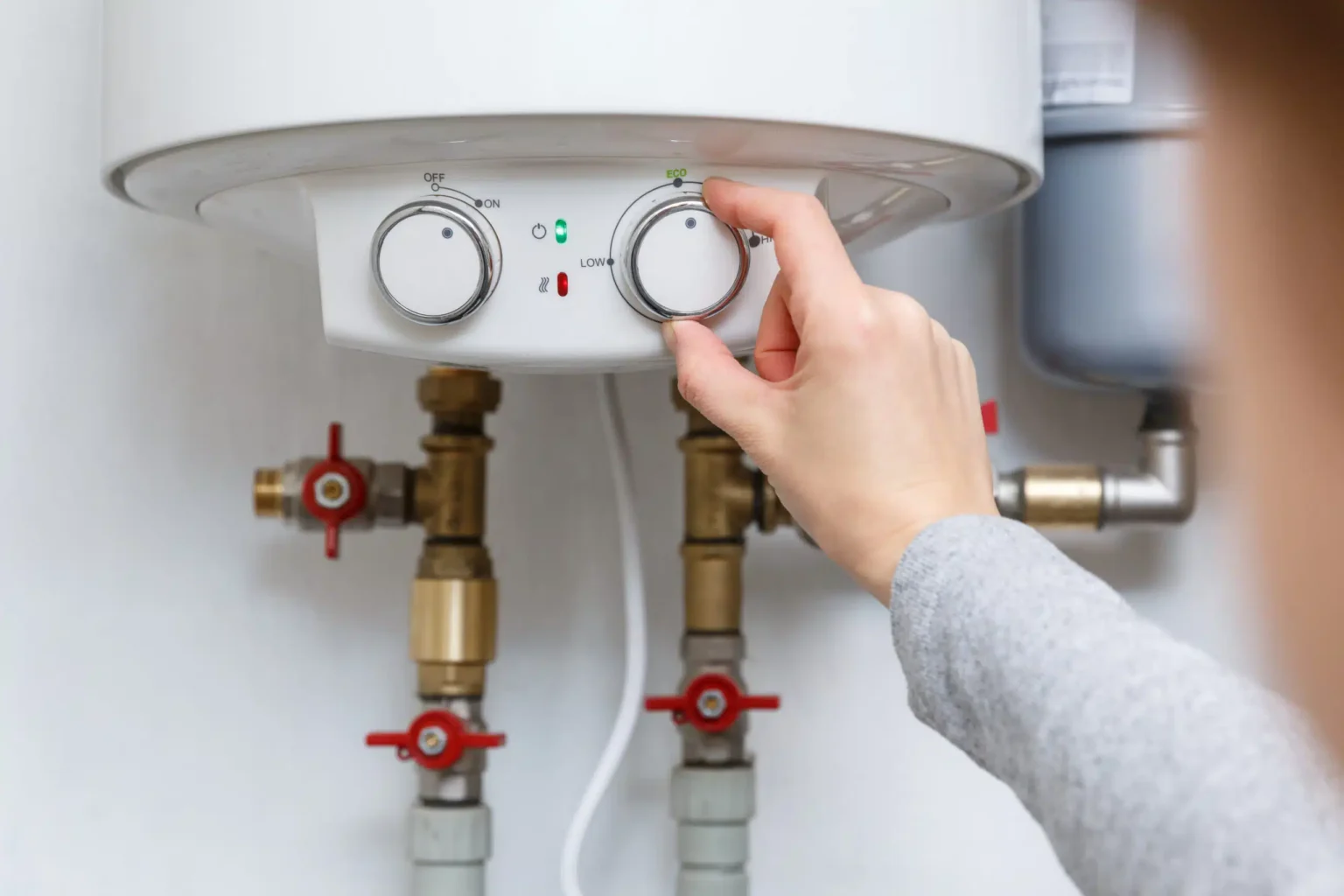Homeowner adjusting the temperature controls on a water heater in West Linn